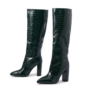 Detail of dark green crocodile embossed knee-high boots with elegant chunky heels