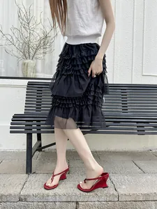 Close-up view of red French minimalist wedge thong sandals worn with elegant black tiered skirt