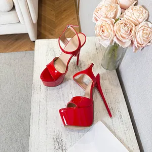 Side view of elegant red patent leather platform high heel sandals on a white table