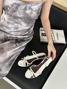 Détail de sandales élégantes à petits talons blanches avec brides fines et semelle bordeaux