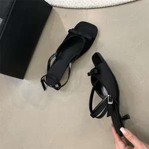 Detail view of elegant black French kitten heel sandals with bow and ankle strap