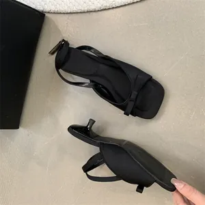 Elegant black kitten heel sandals featuring bow detail and adjustable ankle strap