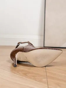 Nahaufnahme der strukturierten Sohle und Krokoprägung eines braunen High-Heel-Stiefels.