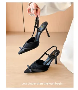 Elegant black satin slingback heels featuring a delicate front bow and pointed toe detail.