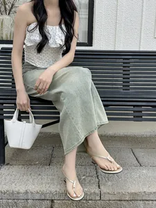 Model wearing French minimalist gold wedge thong sandals on a park bench outdoors.