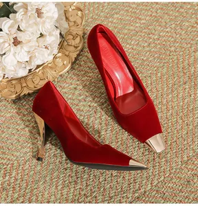 Elegant red velvet high heels with gold pointed metal cap on a vintage background.