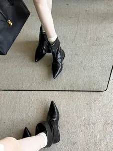 Chic black pointed-toe leather ankle boots with a low heel shown in detail view