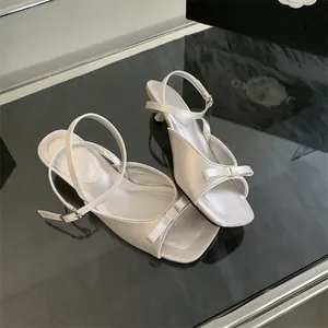 Elegant white satin kitten heel sandals with bow detail and adjustable ankle strap