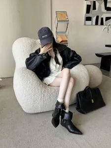 Chic black pointed-toe ankle boots with buckle detail shown on model in modern room