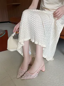 Vista detallada de zapatos de tacón grueso en encaje rosa con perlas elegantes.