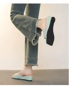 Vista laterale dettagliata di sandali con zeppa intrecciati verde menta indossati con jeans