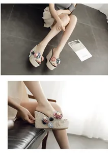 Close-up detail of stylish women's floral wedge sandals with platform woven straw sole.