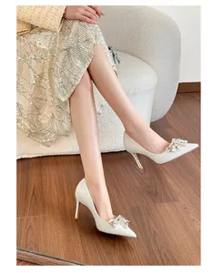 Elegant silver glitter high heels with crystal bow decoration worn by a fashion model