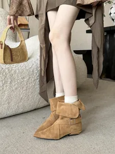 Detailed view of tan suede pointed toe ankle boots with a stylish buckle strap