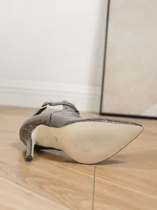 Detailansicht einer grauen Stiefelette mit Krokoprägung, die die Sohle und Textur zeigt