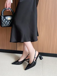 Detalle de sandalias elegantes de encaje negro con punta fina, tacón bloque y cuentas.