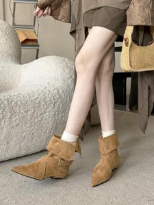 Detailed view of camel suede pointed-toe boots with buckle strap and cuff