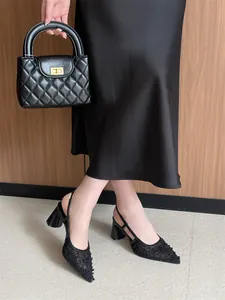 Detalle de los zapatos destalonados de encaje negro con punta y tacón de bloque.