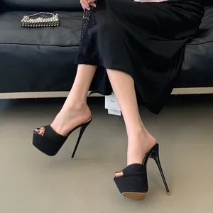 Close-up of black platform high heel mules with a shimmering finish and stiletto heel.