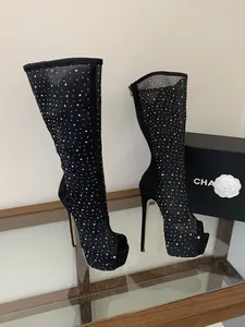 Close-up of black rhinestone mesh long boots with high stiletto heels and platform.