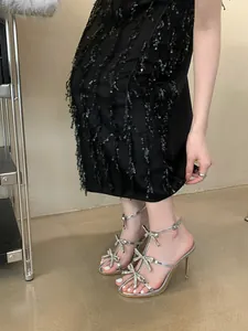Detail view of silver high heel sandals with sparkling rhinestone bows and thin heels