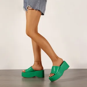 Élégantes sandales à plateforme vertes portées par un mannequin pour un look d'été.