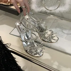 Detailed view of silver high heel sandals decorated with sparkling rhinestone bows