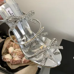Close-up of sparkling rhinestone bows on silver metallic high-heeled sandals