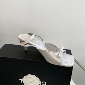 Detailed side view of elegant white satin kitten heel sandal with bow and ankle strap