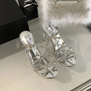 Detailed view of silver stiletto sandals featuring sparkling rhinestone bow straps