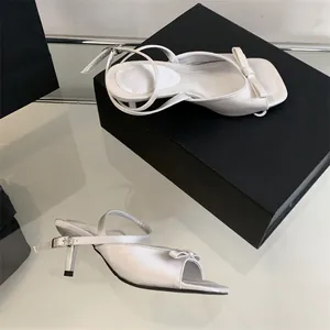 Elegant white satin kitten heel sandals featuring bow detail and adjustable ankle strap