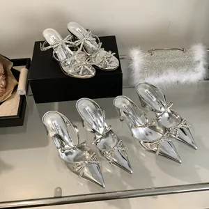 Detailed view of silver stiletto sandals featuring sparkling rhinestone bow decorations