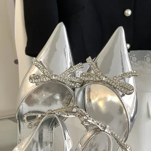 Detailed view of elegant silver pointed-toe heels with sparkling rhinestone double bows decor