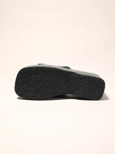 Vue détaillée de la semelle antidérapante des sandales compensées noires pour femmes.