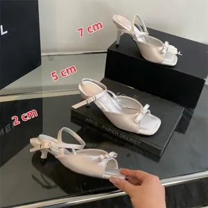 Elegant white stiletto sandals with bows and ankle straps in three heel heights.
