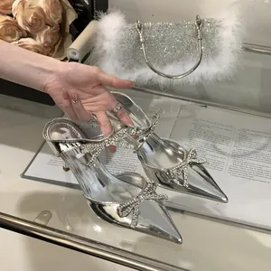 Close-up of silver stiletto sandals featuring sparkling rhinestone bows and a pointed toe