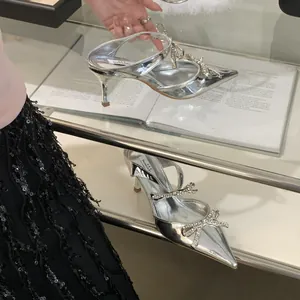 Detailed view of silver pointed-toe heels featuring elegant rhinestone-studded bows