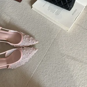Vista detallada de tacones de encaje rosa con delicados adornos de perlas y lentejuelas