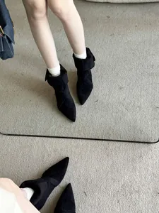 Elegant black pointed-toe suede-finish ankle boots with low heels shown in mirror reflection.