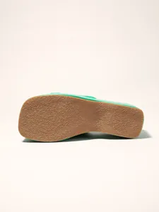 Bottom view showing the textured non-slip sole of a stylish green platform sandal