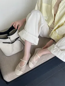 Dettaglio ballerine Mary Jane traforate beige intrecciate indossate da una modella lifestyle
