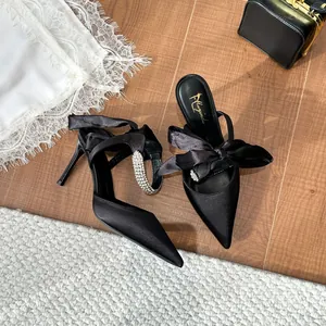 Elegant black stiletto high heels with rhinestone strap and satin ribbon bow details.