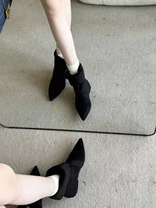 Elegant pointed-toe low heel black ankle boots in a stylish mirror reflection view