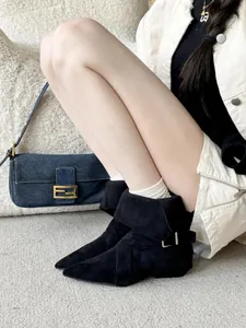 Detail of black pointed-toe suede boots with side buckle and folded cuff