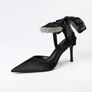 Elegant black pointed-toe satin stilettos with rhinestone ankle strap and bow detail.