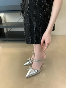 Detail view of silver high heel sandals featuring rhinestone bows and a pointed toe.