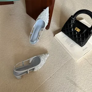 Vista detallada de zapatos destalonados de encaje gris con perlas y tacón grueso