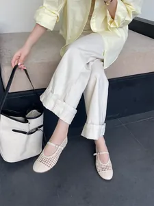 Dettaglio ravvicinato di ballerine Mary Jane intrecciate beige indossate con pantaloni crema.