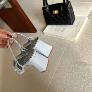 Detalle de sandalias azul claro con tacón de bloque, encaje y perlas