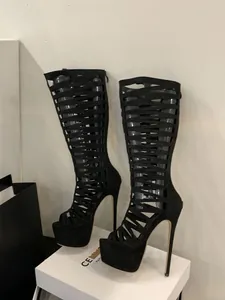 Detail view of black knee-high cutout gladiator boots with platform and stiletto heels.